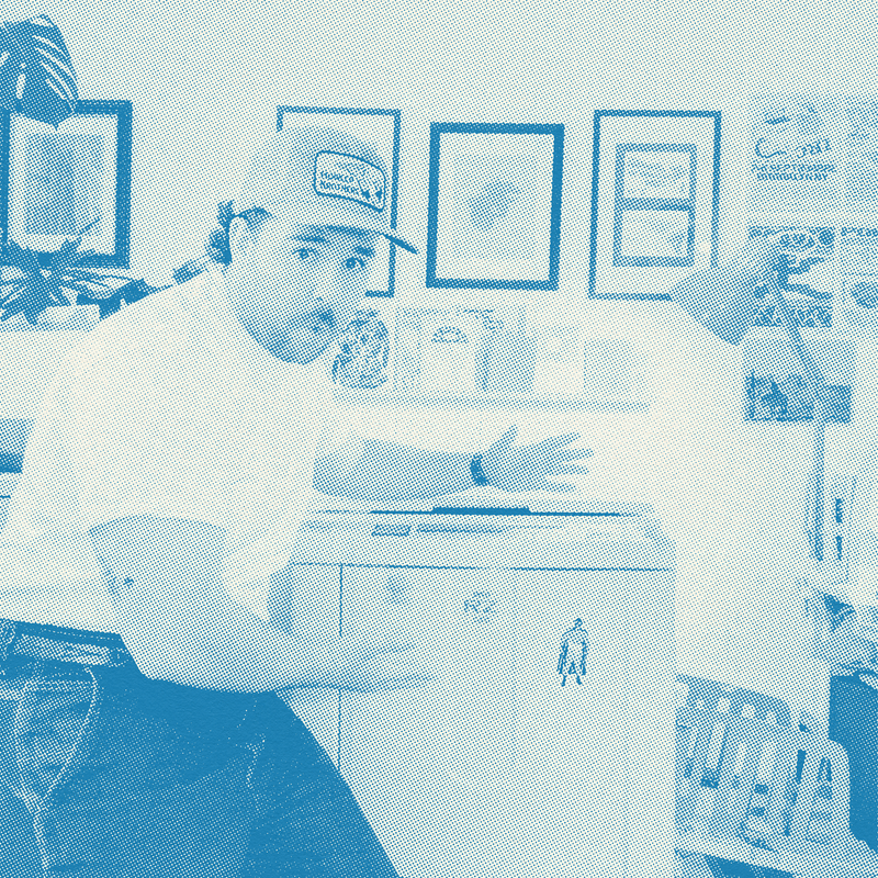 Person wearing a cap and white shirt in a room with framed pictures on the wall.